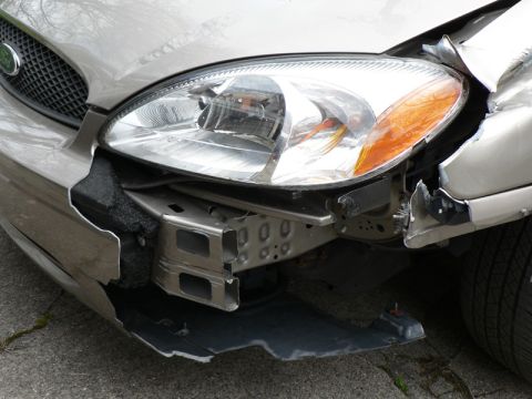 2004 Ford Taurus - The front of a 2004 Ford Taurus shows extensive damage, including a broken bumper and headlight assembly.