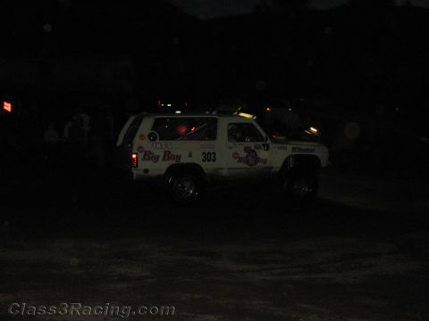 1990 Ford Bronco - white off-road SUV numbered 303 with 'Big Boy' lettering sits on a dark dirt course at night.