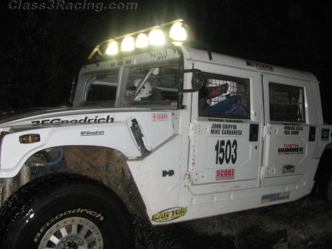 1990 Ford Bronco - white Hummer H1 race vehicle numbered 1503 with BFGoodrich tires and a roof light bar, photographed at night.
