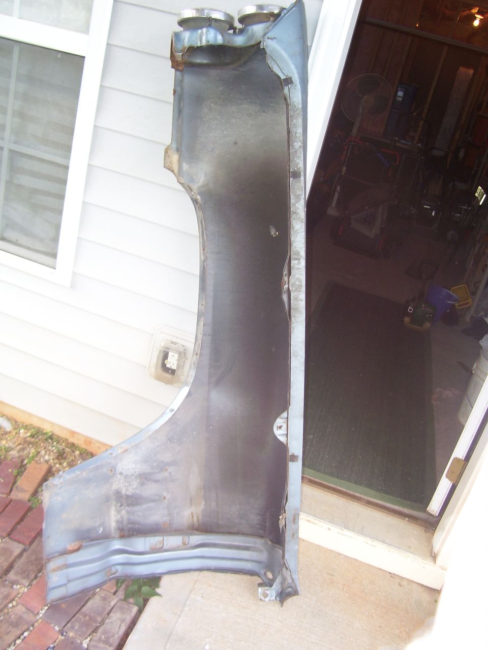 Blue car fender, interior view, showing rust and damage