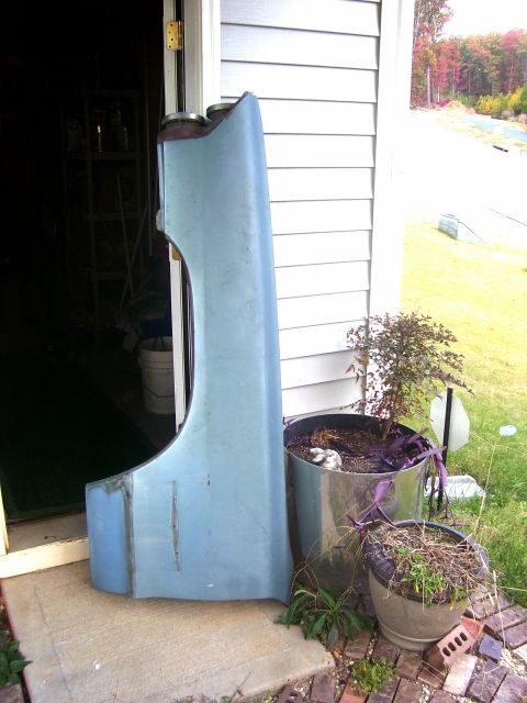1965 Pontiac Bonneville - A light blue fender is propped up outside a garage door.
