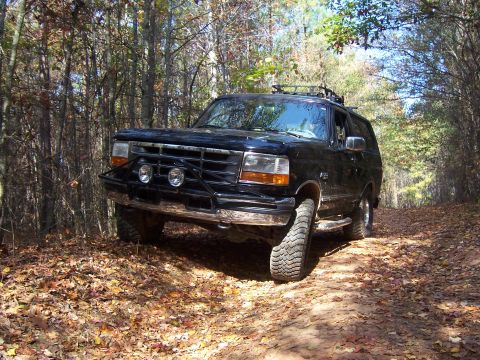 1996 Ford Bronco - This black 1996 Ford Bronco navigates a leaf-covered dirt path through a wooded area.