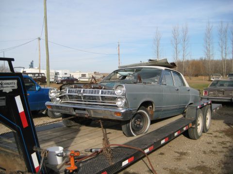 1967 Mercury Cyclone - Gray 1967 Ford Fairlane 500 sedan on a trailer, ready for transport. Engine bay is empty.