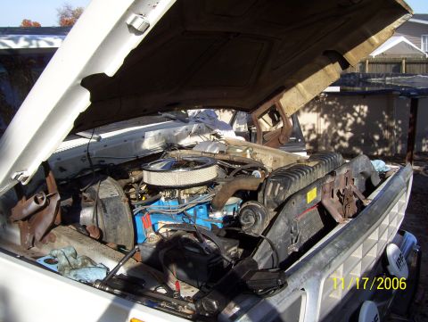 1978 Ford Bronco - The engine compartment of a truck is shown with the hood raised, revealing the motor and associated parts.