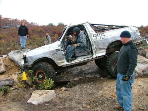1995 Ford Bronco - Modified 1995 Ford Bronco navigating an off-road obstacle course with a roll cage.