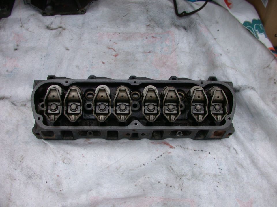 Dirty cast-iron V8 cylinder head with rocker arms and valve springs on a white cloth