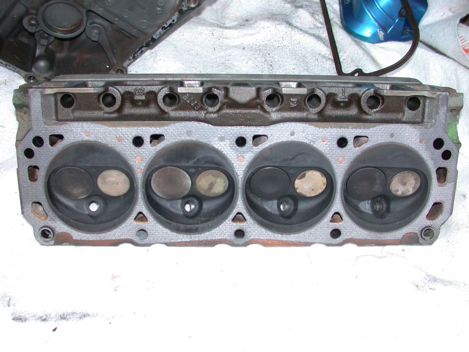 Cast-iron V8 cylinder head with four combustion chambers face-up on a white shop cloth