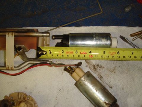 1996 Ford Bronco - Two cylindrical automotive fuel pumps laid on a white shop towel, one new (bright silver with black end and white plastic outlet) and one o…
