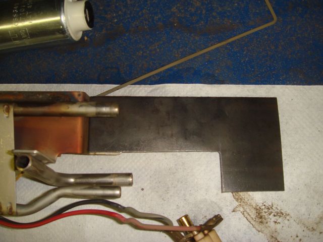 Vehicle part with copper tubing, wires, and dark metal plate on paper towel