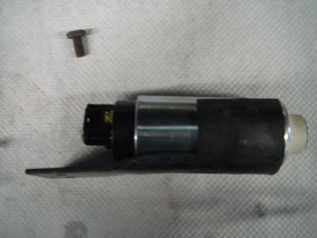 Electric fuel pump with black cap, chrome body and mounting bracket next to a bolt.