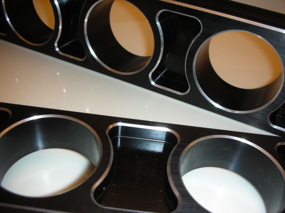 Close-up of machined lightening holes in black anodized aluminum arms