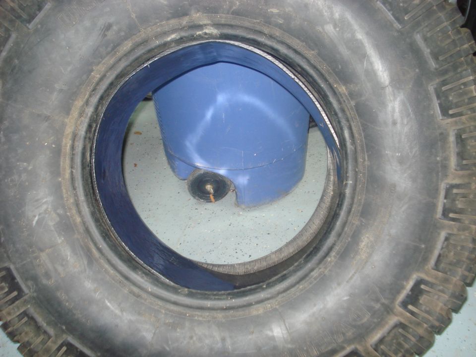 Off-road tire laid over a blue fuel or fluid tank