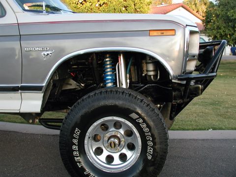 1980 Ford Bronco - Close-up of the front fender and wheel well of a 1980 Ford Bronco, showing off its suspension and off-road tire.