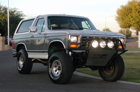 1980 Ford Bronco - Modified 1978 Ford Bronco with custom front bumper and auxiliary lights sits on a paved road.