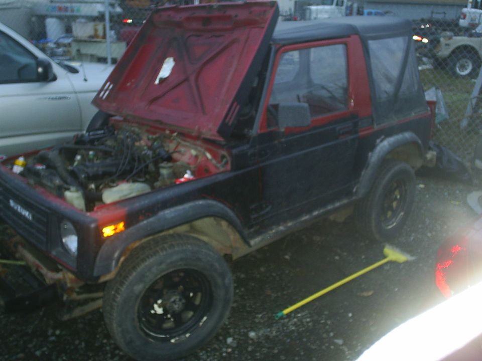 Suzuki Samurai with hood open, showing engine bay. Black body with red interior and soft top