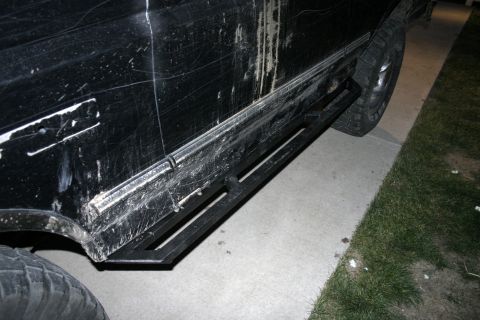 1994 Ford Bronco - Side view of a black SUV with aftermarket sliders, showing significant wear and tear on the body.