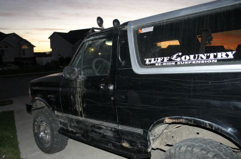1994 Ford Bronco - Side view of a black 1994 Ford Bronco with off-road suspension stickers.