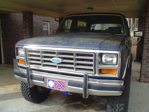 1984 Ford Bronco - This Ford Bronco is parked under a covered area, showing its front grille and bumper.
