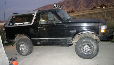 1994 Ford Bronco - This black Ford Bronco features a lifted suspension, aftermarket wheels, and roof lights, with a "4 Wheel Parts" sticker visible on the rea…