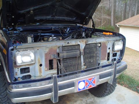 1984 Ford Bronco - Blue Ford truck front end with hood open, displaying the engine and radiator area.