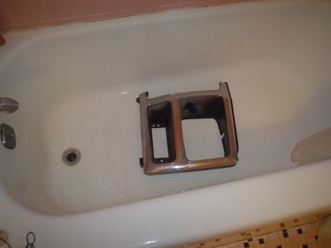 1984 Ford Bronco - A chrome trim piece is being cleaned in a bathtub.