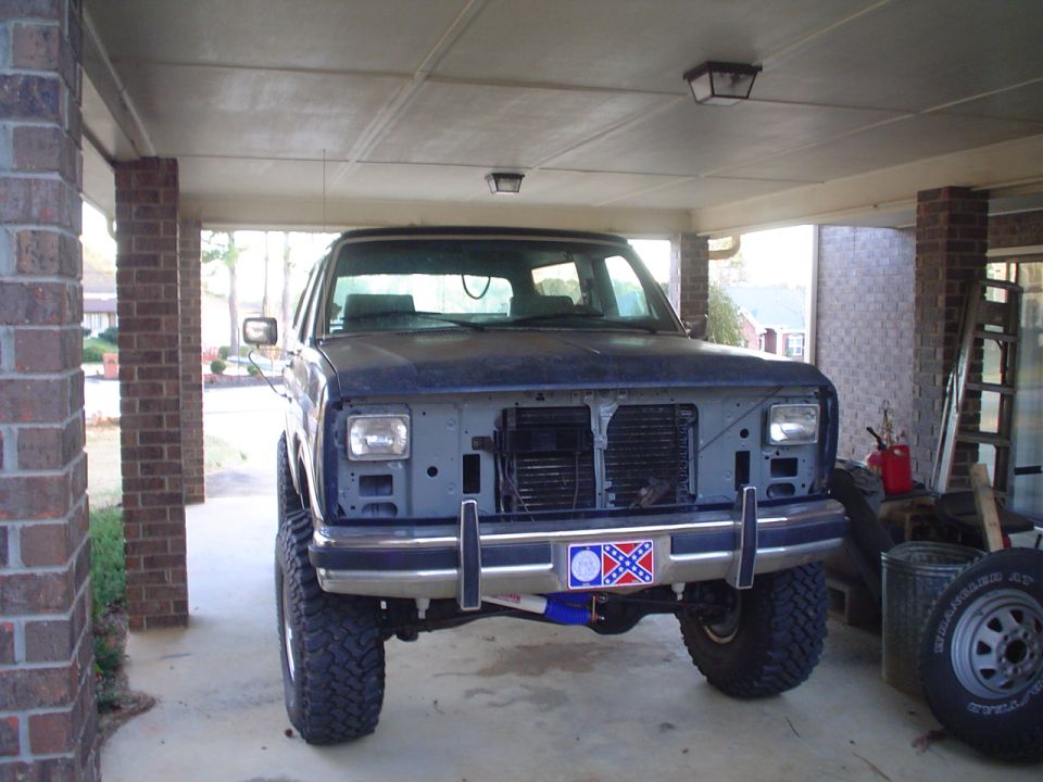 Dark blue SUV front view, missing grille and headlights, lifted suspension