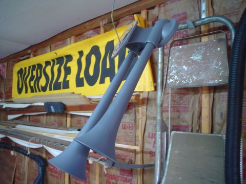 1984 Ford Bronco - Air horns hanging in a garage with an 'OVERSIZE LOAD' banner behind them.