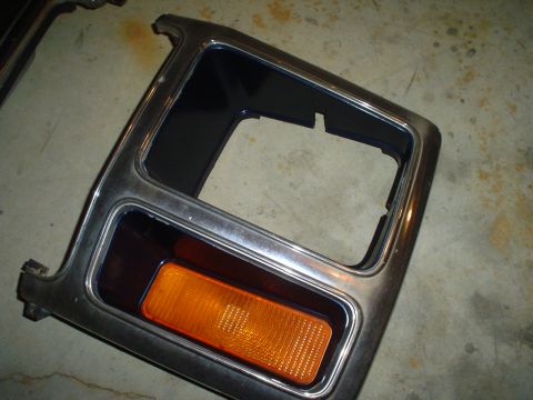 1984 Ford Bronco - A detached vehicle bumper trim piece with an amber turn signal is shown against a concrete background.