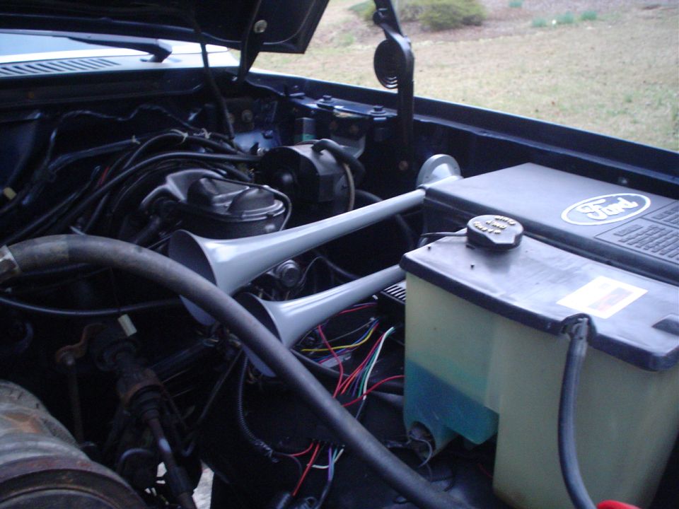 1984 Ford Bronco engine bay with dual air horns and Ford logo on cover