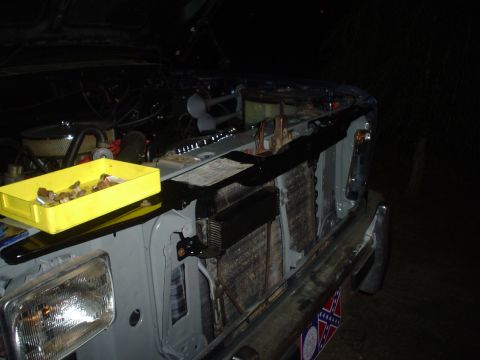 1984 Ford Bronco - Front end of a vehicle with hood open, parts tray on fender, and radiator exposed.