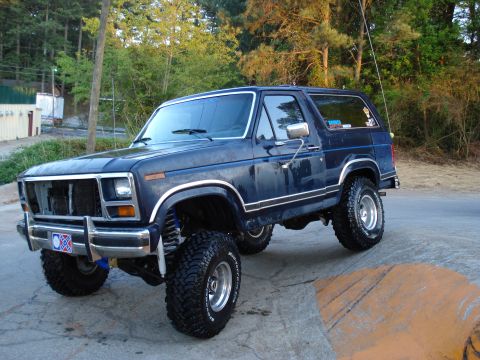1984 Ford Bronco - This lifted 1980 Ford Bronco features a dark blue paint job with chrome accents and aggressive off-road tires.