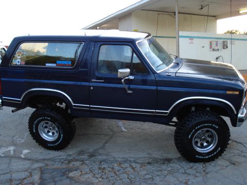 1984 Ford Bronco - Side view of a lifted Ford Bronco with off-road tires and a Bronco sticker on the window.