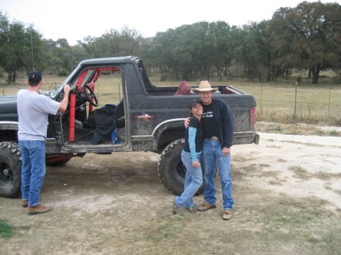 2001 Jeep Wrangler - A black off-road SUV with a red roll cage and lifted suspension is parked on a dirt road with people standing nearby.