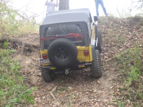 2001 Jeep Wrangler - A yellow Jeep Wrangler navigates an off-road trail, with people watching from the top of the incline.