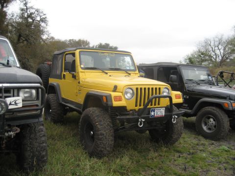 2001 Jeep Wrangler - A yellow 2001 Jeep Wrangler is parked next to a black Jeep, with another vehicle partially visible on the left.