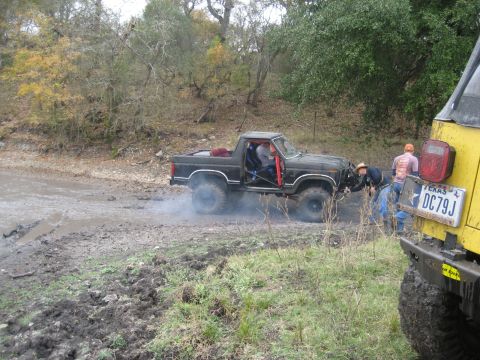 2001 Jeep Wrangler - Two vehicles are stuck in the mud on an overcast day, with people attempting to free one of them.