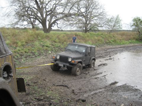 2001 Jeep Wrangler - A Jeep Wrangler is being towed out of a muddy area near a body of water.