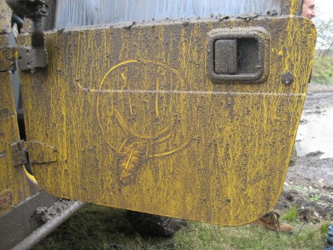 2001 Jeep Wrangler - Mud splatters cover the yellow door of a Jeep, obscuring most of the vehicle's details but revealing a smiley face design.