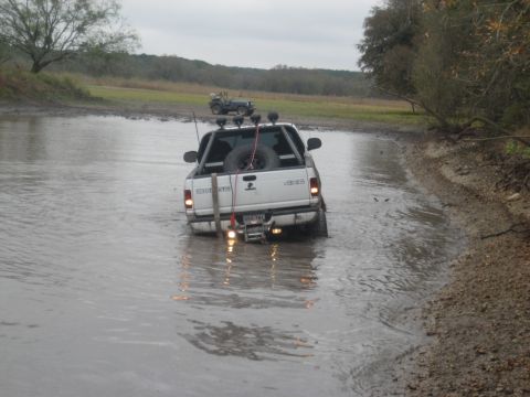 2001 Jeep Wrangler - Two off-road vehicles navigate a muddy water crossing on an overcast day.