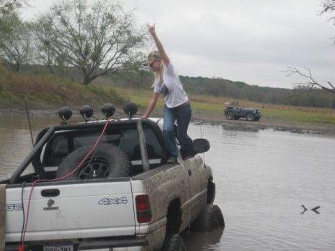 2001 Jeep Wrangler - Two off-road vehicles are partially submerged in muddy water on a cloudy day.