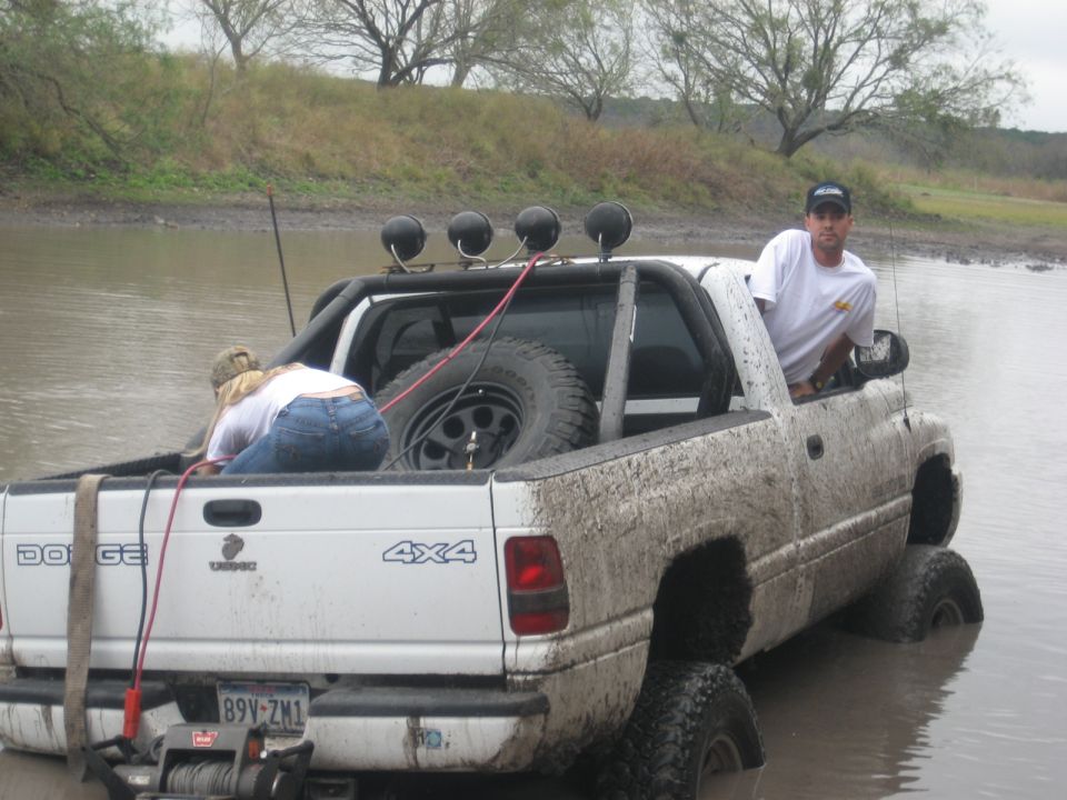 White Dodge 4x4 pickup truck stuck in mud, rear view