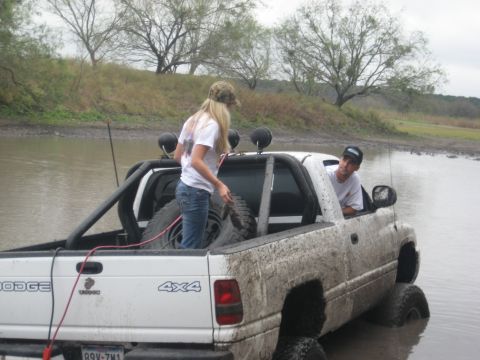 2001 Jeep Wrangler - A white Dodge Ram pickup truck is partially submerged in muddy water, with two people visible.