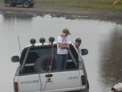 2001 Jeep Wrangler - A white Dodge pickup truck with 4x4 badging is partially submerged in water, with two people standing in the truck bed.