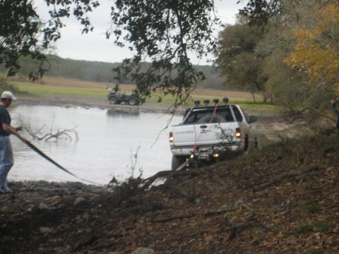 2001 Jeep Wrangler - A white pickup truck is stuck in the mud near a body of water, with an ATV visible in the distance.