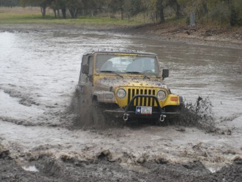 2001 Jeep Wrangler - Yellow 2001 Jeep Wrangler navigates a challenging muddy off-road path.