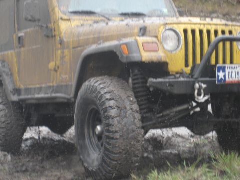 2001 Jeep Wrangler - This Jeep Wrangler is covered in mud as it navigates a challenging off-road terrain.