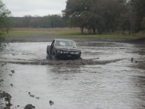 2001 Jeep Wrangler - Pickup truck navigates a muddy water obstacle in an off-road setting.