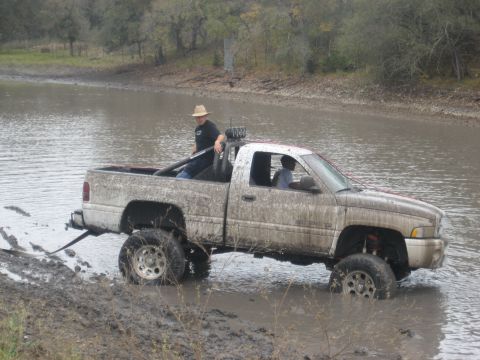 2001 Jeep Wrangler - Pickup truck stuck in water, with one person in the driver's seat and another in the bed.