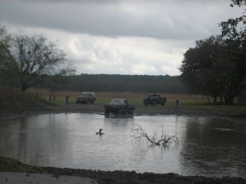 2001 Jeep Wrangler - Several vehicles are gathered around a muddy area with a pond, under a cloudy sky.