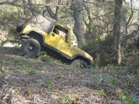 2001 Jeep Wrangler - A yellow 2001 Jeep Wrangler is seen navigating a steep, wooded incline.